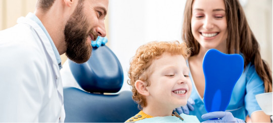 smiling-boy-sitting-in-dental-chair-with-dentists