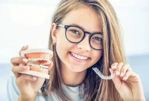 Teen holding braces and Invisalign to compare