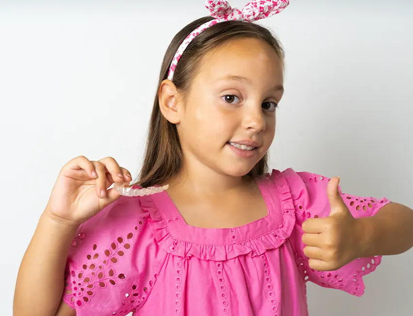 Kid holding Invisalign clear aligners in Carlsbad, CA